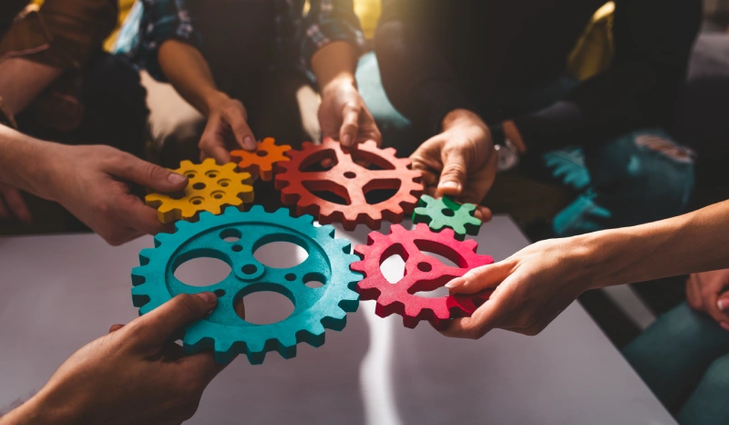 A group of people holding up colorful gears.