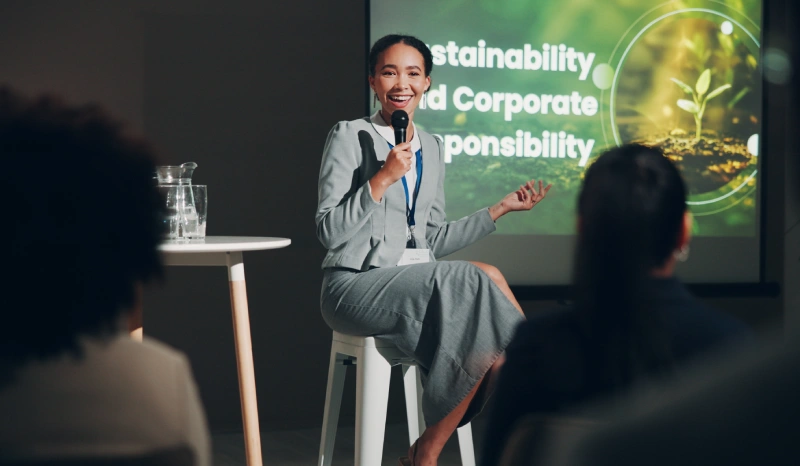 A woman is speaking at an event with microphone.