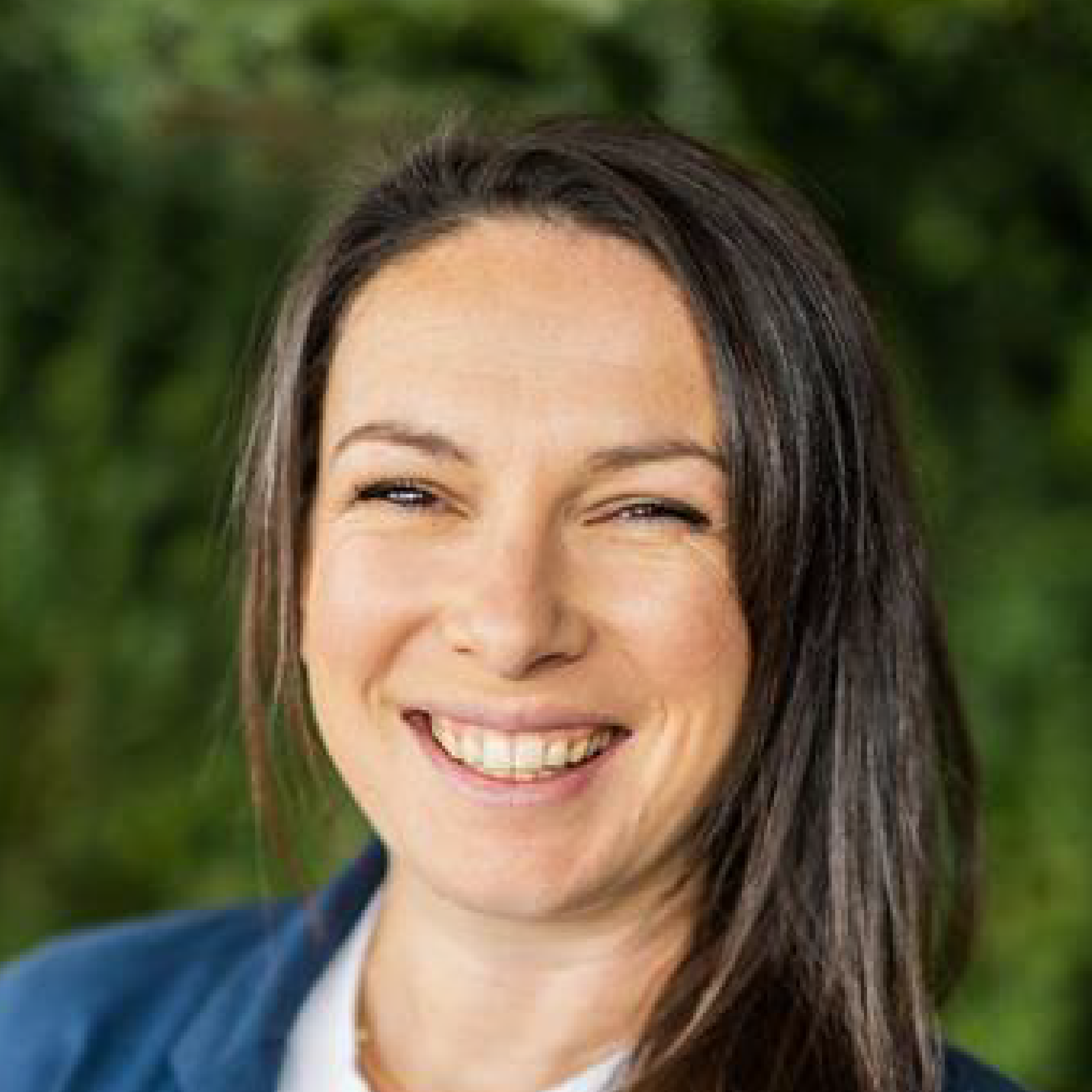 Smiling woman with long hair outdoors.