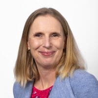 Smiling woman in blue blazer, white background.