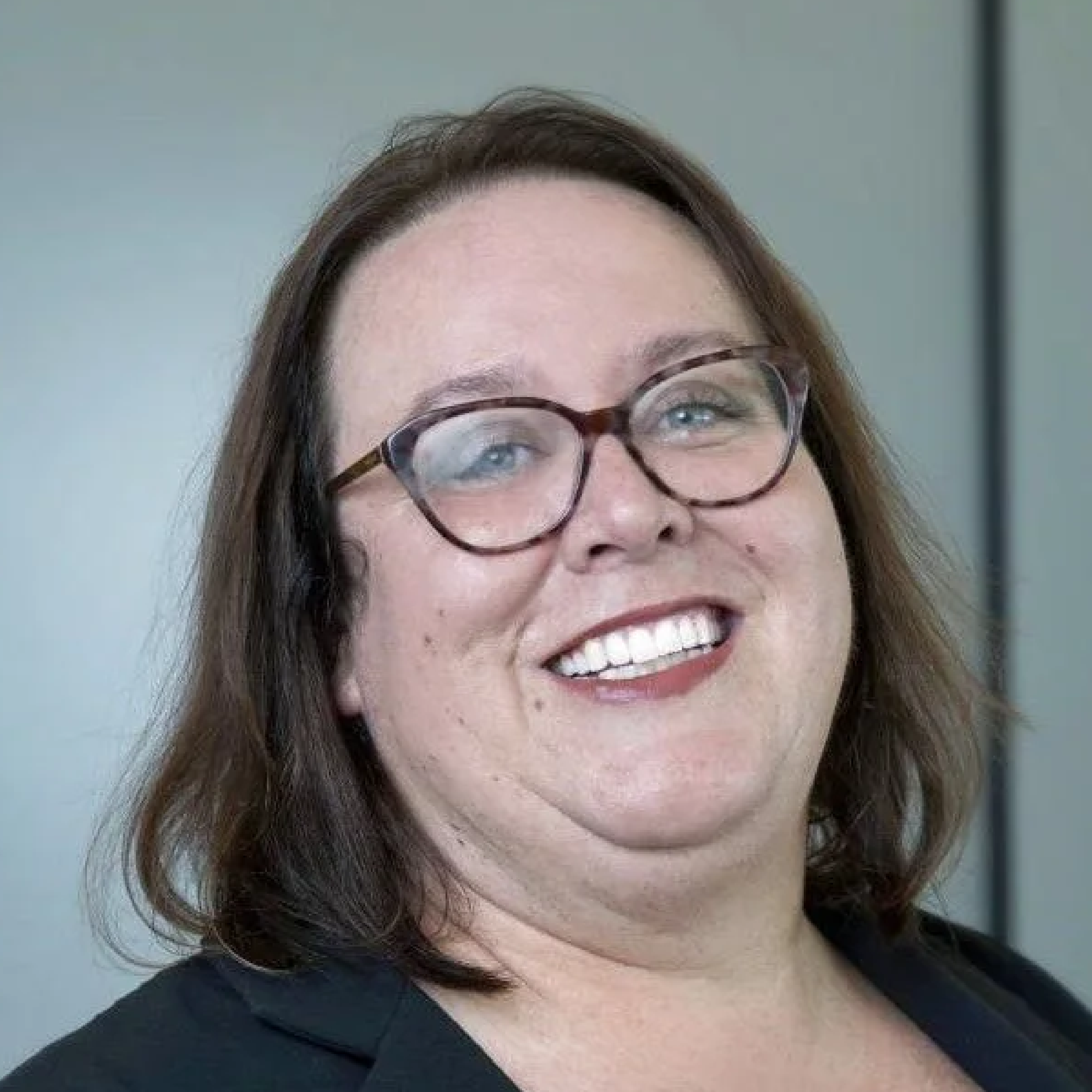 Smiling person wearing glasses, professional setting.