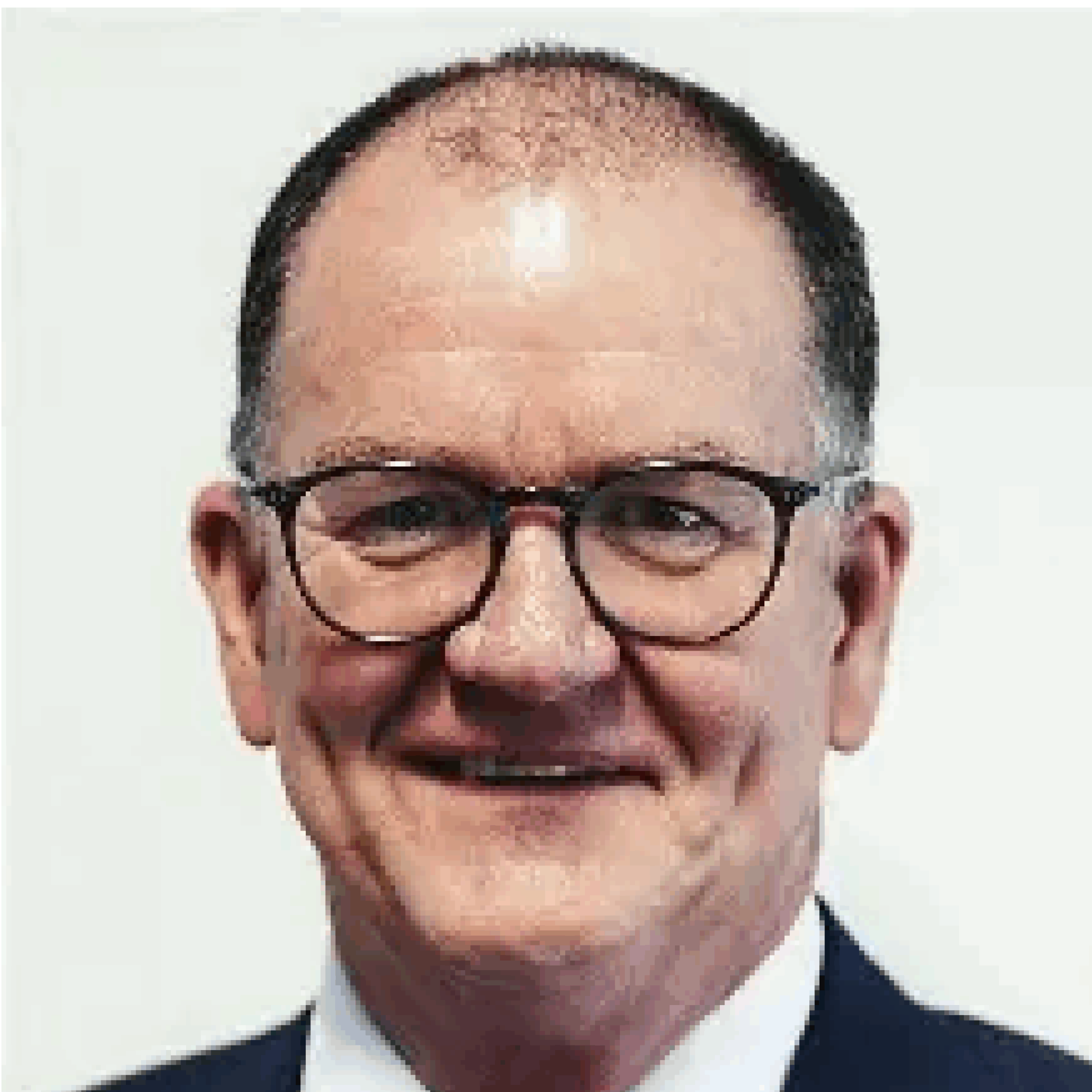 Man wearing glasses and a suit, smiling.