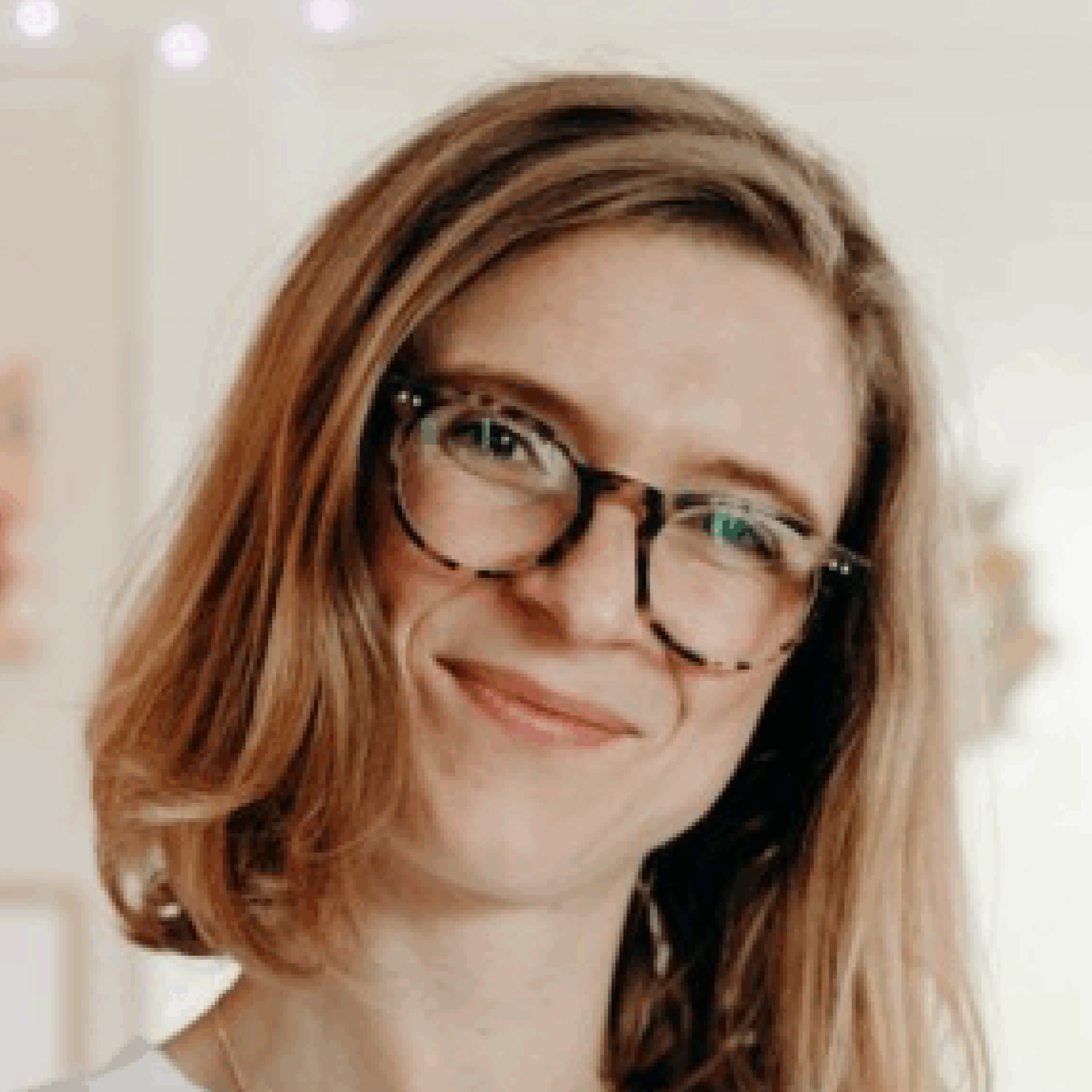 Smiling woman with glasses and brown hair.