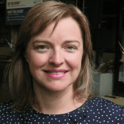 Smiling woman in a polka dot blouse.