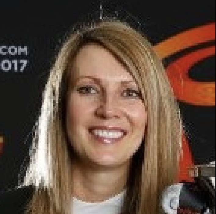 Smiling person at event with dark background.