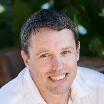 Smiling man in a white shirt outside.