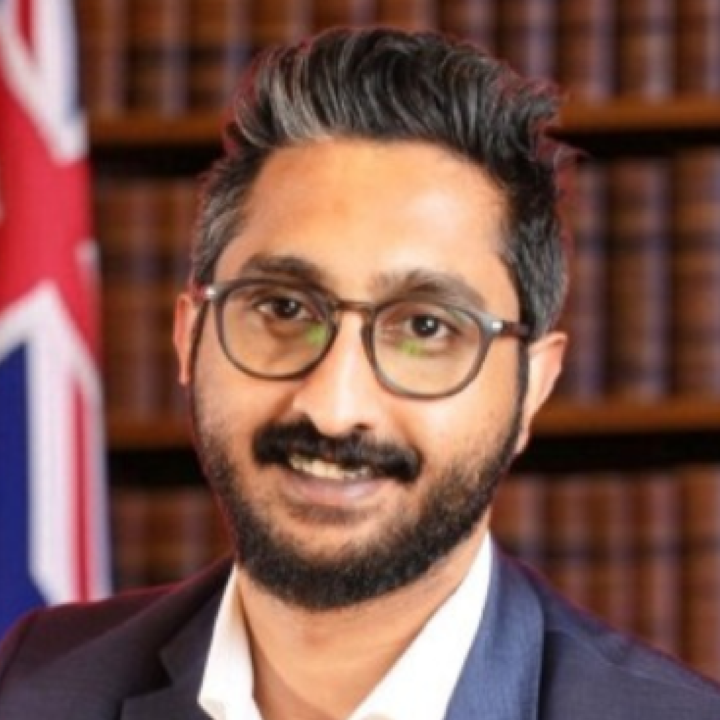 Man with glasses and beard, Australian flag background.